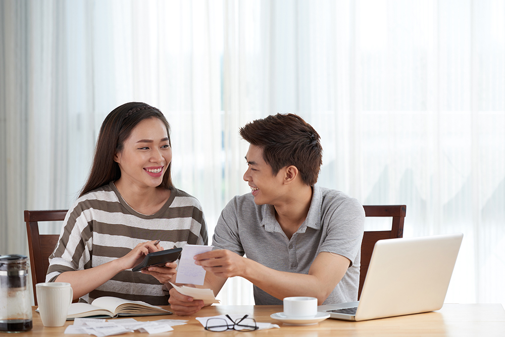 A man and woman smiling while doing taxes